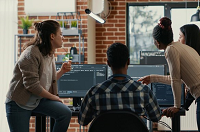 Equipe de tecnologia reunida em mesa de trabalho com laptops, sugerindo avaliação de clima organizacional.